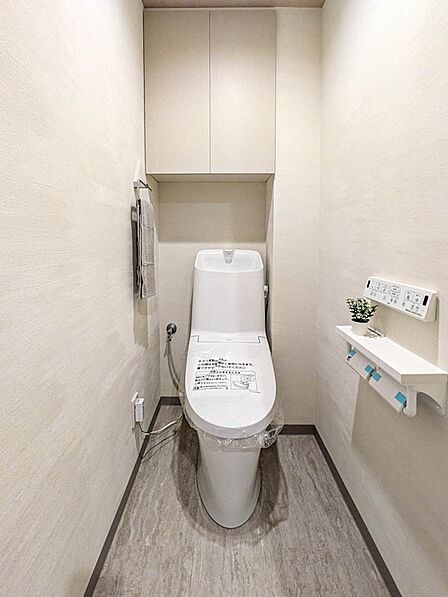 温水洗浄機能付きトイレに新規交換。上部に吊戸棚を備えており、ストック類をすっきり収納できます。