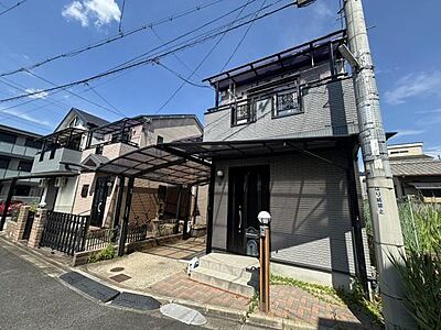外観:落ち着いたダークカラーが目を引く2階建て住宅。屋根付きの駐車スペースで、雨の日の乗り降りもスムーズです。 外観:落ち着いたダークカラーが目を引く2階建て住宅。屋根付きの駐車スペースで、雨の日の乗り降りもスムーズです。