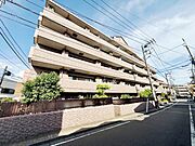 落ち着いた色合いの外観が印象的なマンションです。角地に位置しており開放感があります。道路に面した立地でアクセスの良さも感じられます。周囲には植栽が施され清潔感があります。