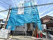 建築中の様子が見られる外観です。現場の進行状況や作業の様子がうかがえます。周辺環境との調和も意識された立地です。青いシートで覆われ安全対策も施されています。