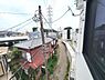 その他：現地からの眺望の写真です。窓から見える周辺の様子を確認できます。近隣の建物や道路の雰囲気を把握しやすい一枚です。電柱や配線も映り現地のリアルな状況が伝わります。ゆったりとした道幅の道路が続いています。