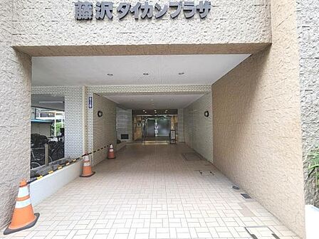 エントランスは広々とした印象で建物へのアプローチがゆったりとしています。明るいタイル張りが清潔感を演出しています。視認性の高い館名サインがあり訪問者にも分かりやすい設計です。
