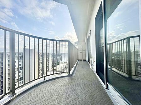 ワイドなバルコニーが開放感を演出しています。高層階からの景色を一望できます。大きなガラス窓がバルコニーと室内をつなげています。光が差し込みやすく明るい印象です。手すりがしっかり設置されています。