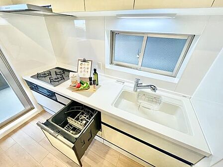 広々としたカウンターに加えシンクやガスコンロの配置が使いやすく設計されています。食器洗い乾燥機が搭載されており日々の家事をサポートします。窓があり明るい雰囲気が感じられます。