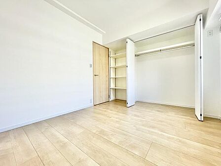明るい光が差し込む寝室です。広々とした空間がありさまざまなレイアウトが可能です。クローゼットには収納棚もあり使いやすさが特徴です。シンプルな内装で多様なインテリアに対応できます。