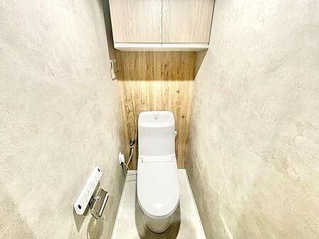 シンプルですっきりとしたデザインのトイレです。壁面の木目調が温かみを演出します。収納スペースが確保されていて整理しやすい印象です。落ち着いたカラーリングで空間が明るく感じられます。
