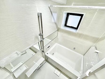 明るい光が差し込むバス空間です。窓付きで換気がしやすく清潔感のあるデザインとなっています。ミラーや手すりも設置され快適にご利用いただけます。浴槽も広めに設計されています。