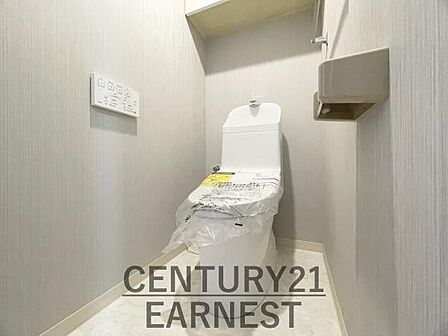 シンプルで清潔感のあるトイレ空間です。独立したスペースで使いやすい仕様となっています。壁面の操作パネルや収納棚が配置されており利便性にも配慮されています。明るい色合いの内装が特徴です。