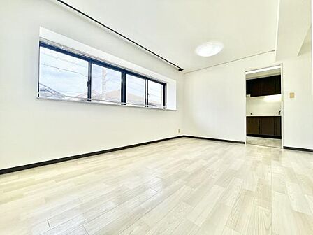 大きな窓から光が差し込む明るいリビングです。白を基調とした内装が清潔感を演出します。隣接するキッチンへの動線もスムーズです。ゆとりある広さが魅力の空間です。快適に過ごせる環境が整っています。