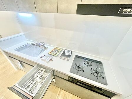 シンプルで機能的なキッチンです。三口コンロが備わっており調理スペースも充実しています。食器洗い乾燥機が設置されているため後片付けがスムーズです。全体的に清潔感があります。