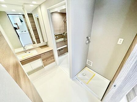 洗面台・洗面所は明るい照明と広々とした空間が特徴です。収納スペースも豊富にありシンプルなデザインが魅力です。隣接する浴室への動線もスムーズで使いやすい配置です。