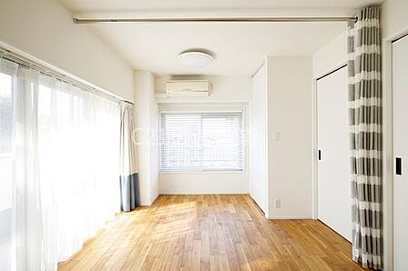明るい光が差し込む洋室です。床は木目のフローリングで落ち着いた雰囲気を持っています。収納やカーテンレールなど使い勝手に配慮されています。窓が多く通風も良好です。清潔感のある内装です。