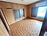 洋室：木目調の壁とフローリングが落ち着いた雰囲気を演出しています。二面採光で日当たりもしっかり確保されています。ゆとりの広さが魅力の洋室です。