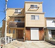 淡いクリーム色の外壁と木調パネルが温かみある風格を演出する3階建て戸建。重厚感ある木製玄関扉と雨戸シャッターで防犯面も安心。2階バルコニーからの開放感も魅力で、上質な住まいをお探しの方にぴったりです。