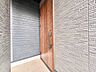 玄関：木製ドアとシャッターのある住宅の玄関部分です