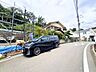 外観：坂道沿いに建つ住宅と駐車中の車の様子