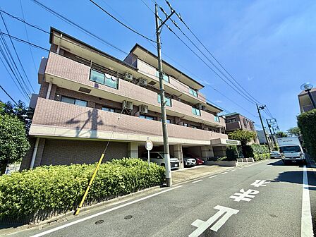 周辺道路と植栽のあるマンション外観