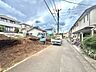 周辺：住宅街の整備された道路と建築中の敷地が見える風景