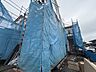外観：青い養生シートで覆われた建築中の建物
