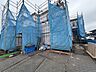 外観：青い養生シートで覆われた建築中の建物