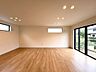リビング/ダイニング：木目調の床と大きな窓がある明るい室内