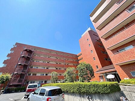 複数階建てのマンション外観と駐車場を撮影した写真です