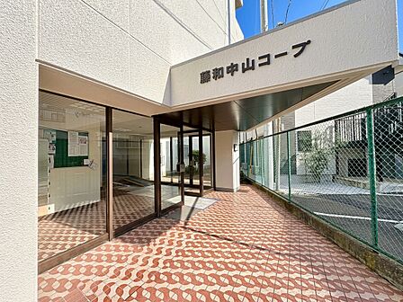 ガラス張りのマンションエントランスと屋外通路の様子