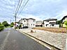 外観：住宅街の整備された道路沿いの空地と周辺の住宅