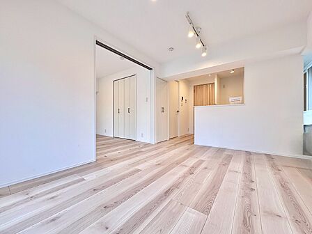 明るい室内木目調の床と対面キッチンを備える