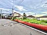 周辺：道路沿いの住宅街赤い柵と戸建てが見える