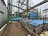 外観：建築中の建物と青い養生シートが見える敷地