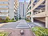外観：集合住宅に囲まれた敷地内の通路と植栽