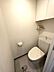 トイレ：清潔感のある白を基調としたトイレです。上部には扉付きの収納棚があり、トイレットペーパー等の保管に便利。