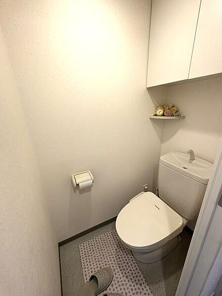 清潔感のある白を基調としたトイレです。上部には扉付きの収納棚があり、トイレットペーパー等の保管に便利。