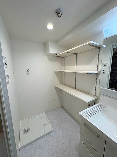 【洗面所】洗濯機置き場。隣には洗剤やタオルなどの収納に便利な可動棚が設置されております。