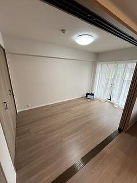 明るい光が差し込む洋室です。広々とした空間が確保されており開放感があります。スライドドアで空間の使い分けが可能です。フローリングが落ち着いた雰囲気を演出しています。収納スペースも用意されています。