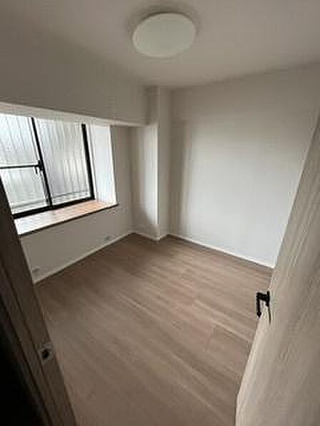 ナチュラルなフローリングが特徴的な洋室です。窓から自然光が入りやすい造りとなっています。シンプルな内装で使い勝手の良い空間です。開放感のあるレイアウトで様々な使い方ができます。