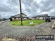 広々とした敷地が魅力の外観写真です。周辺には住宅が並び落ち着いた雰囲気が感じられます。角地に位置しているため開放感があります。整備された道路と歩道が日々の利用に便利です。
