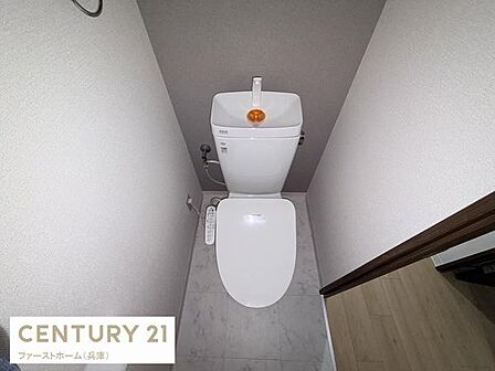 シンプルなデザインで清潔感のあるトイレです。床や壁は落ち着いた色調で統一されており使いやすさが感じられます。温水洗浄便座が設置されており快適な環境が整っています。空間を有効活用したレイアウトです。