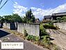 外観：現地土地写真では周辺の自然な緑が魅力的に映えています。道路に面したシンプルなブロック塀が確認できます。日当たりもしっかり感じられる一枚です。車の進入が可能なアプローチも確認できます。