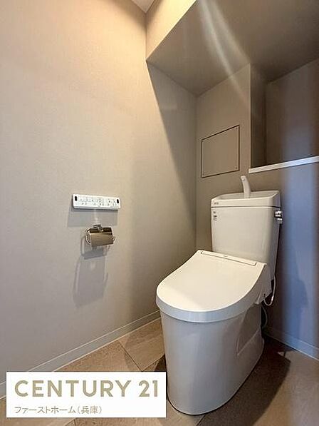シンプルで清潔感のあるトイレ空間です。落ち着いた色合いの壁と床が印象的です。スペースにゆとりがあり使いやすさが感じられます。手洗い付きで機能的なデザインです。