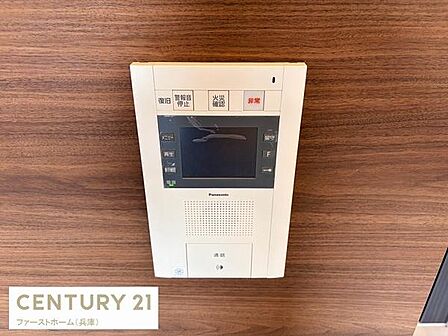 シンプルなデザインのテレビモニター付きインターホンが設置されています。来訪者の確認ができるため安心感があります。操作ボタンが見やすく使いやすい設計です。壁面の木目調とマッチしています。
