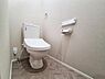 トイレ：落ち着いた色合いのクロスと床材が印象的なトイレです。手元の操作パネルやペーパーホルダーも設置され使いやすさに配慮されています。空間がすっきりと見えるデザインです。