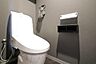 トイレ：シンプルで落ち着いた雰囲気のトイレです。壁の色合いが空間を引き締めています。操作しやすい設備が整っています。ペーパーホルダーや収納も使いやすさを考慮しています。清潔感のある仕様です。