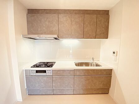壁付のキッチンは上部に収納が作りやすいのがメリット。空間を有効活用したすっきりとしたデザイン。 